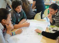 People pointing to a large map spread out on the table in front of them.