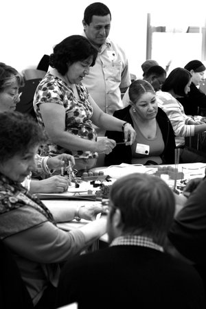 Adults gathered around tables work with "found objects" during an interactive workshop