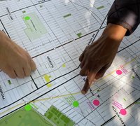 Two different people's hands point at spots on a large map with colored dot stickers placed on it