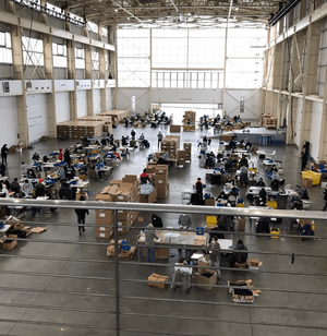 A large open factory floor set up as makeshift production space for Personal Protective Equipment