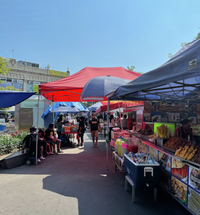 Brighly colored shade tents cover an open plaza with food vendors set up underneath them